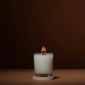 A candle is lit on the table in front of a brown background.