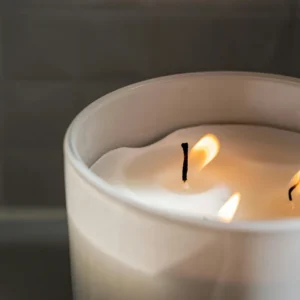 A candle lit in a white bowl on top of a table.
